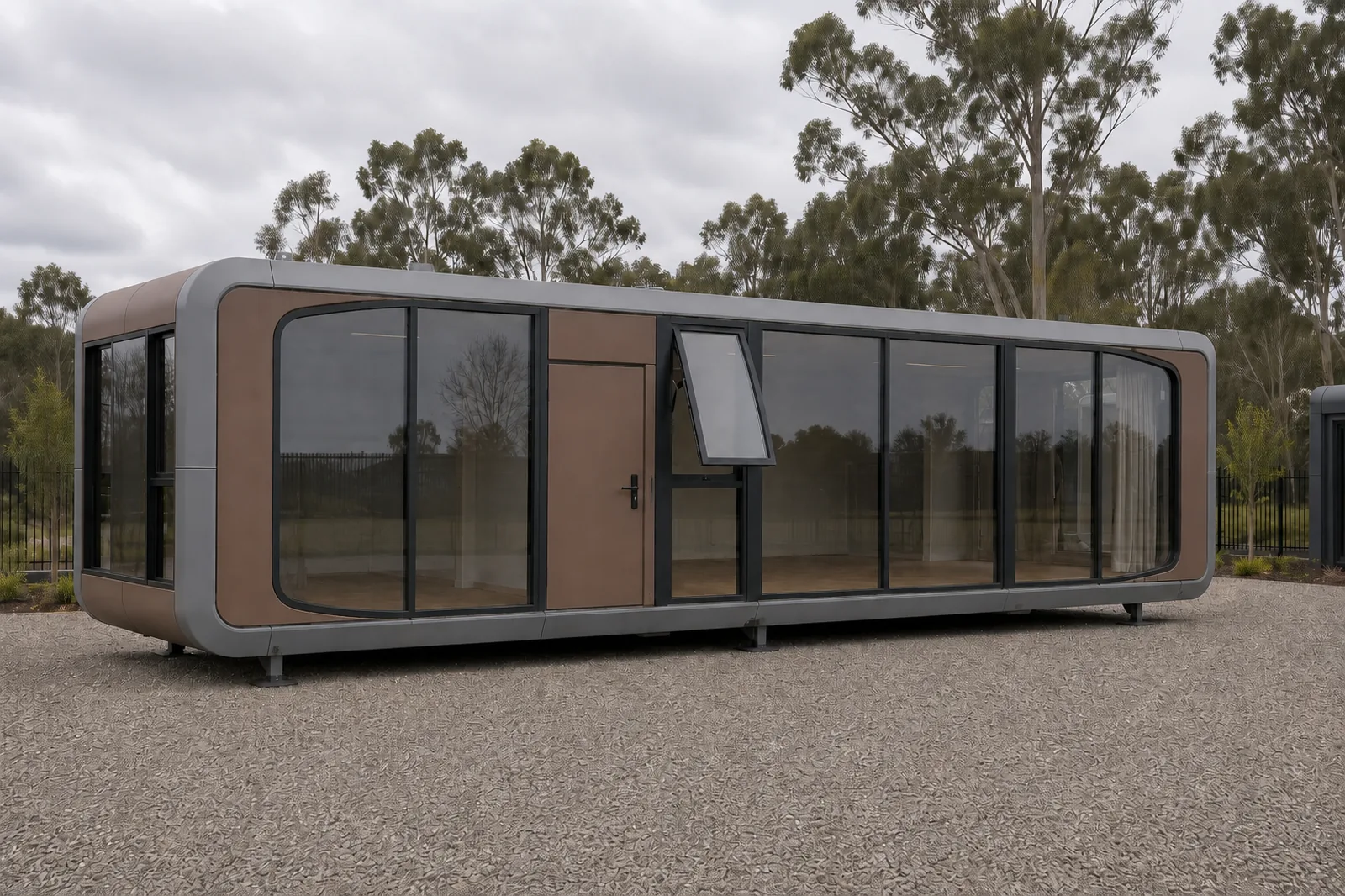 Bronze and grey capsule home from the entry end, glazed nose, a solid entry door and an awning window propped open, gum trees behind