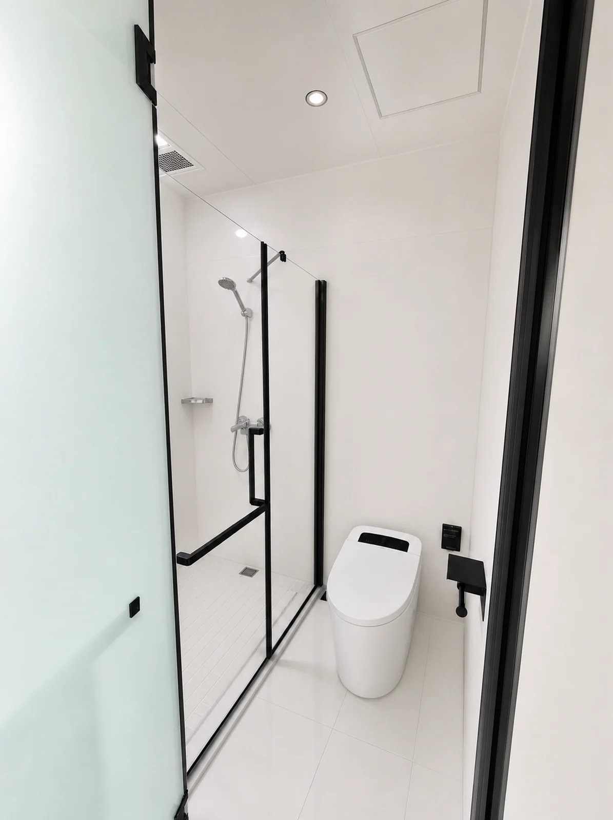 Bathroom in the capsule home, walk in shower behind a black framed glass screen with a wall mounted toilet alongside