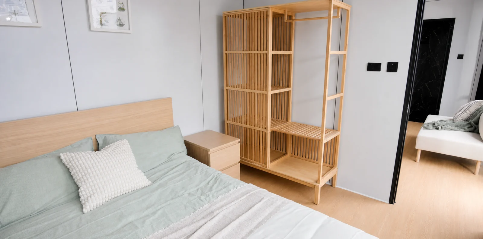 Bedroom in the 8.5 m home, double bed with sage bedding and a slatted timber shelving unit dividing it from the living area