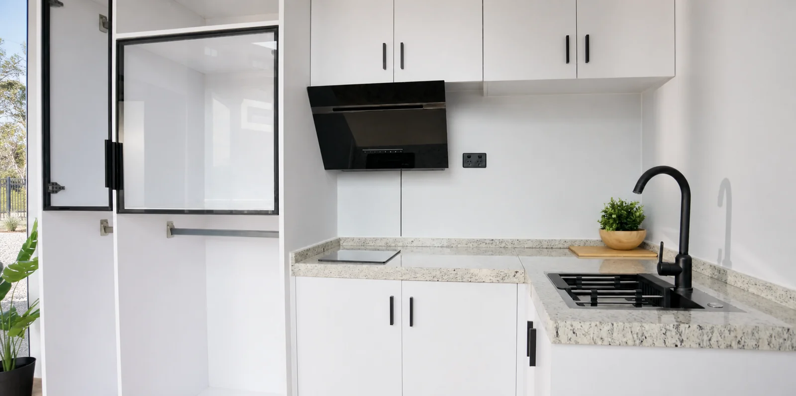Kitchen detail in the 8.5 m home, speckled bench with a gas cooktop, undermount sink and black mixer under white overhead cupboards