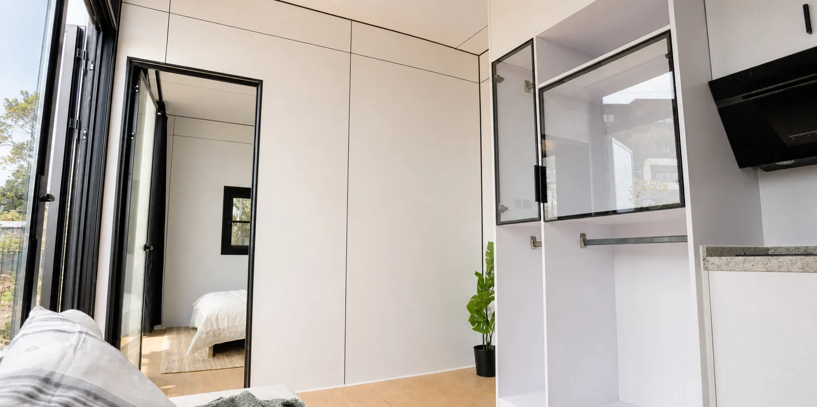 Living area of the 8.5 m home looking to the glazed entry, with the bedroom visible through the doorway and a sofa in the foreground