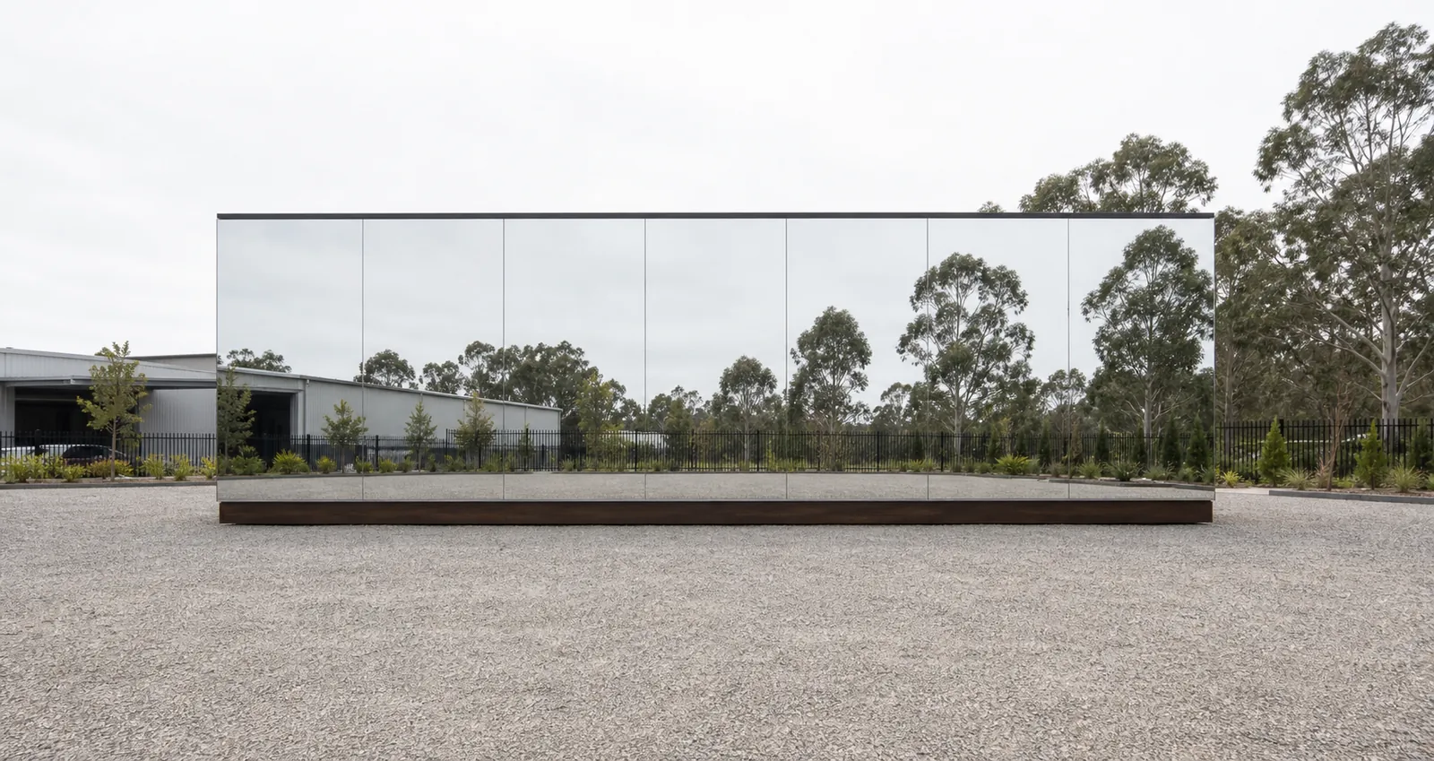 MH115 mirror house showing the full 11.5 metre reflective glass wall on a gravel pad