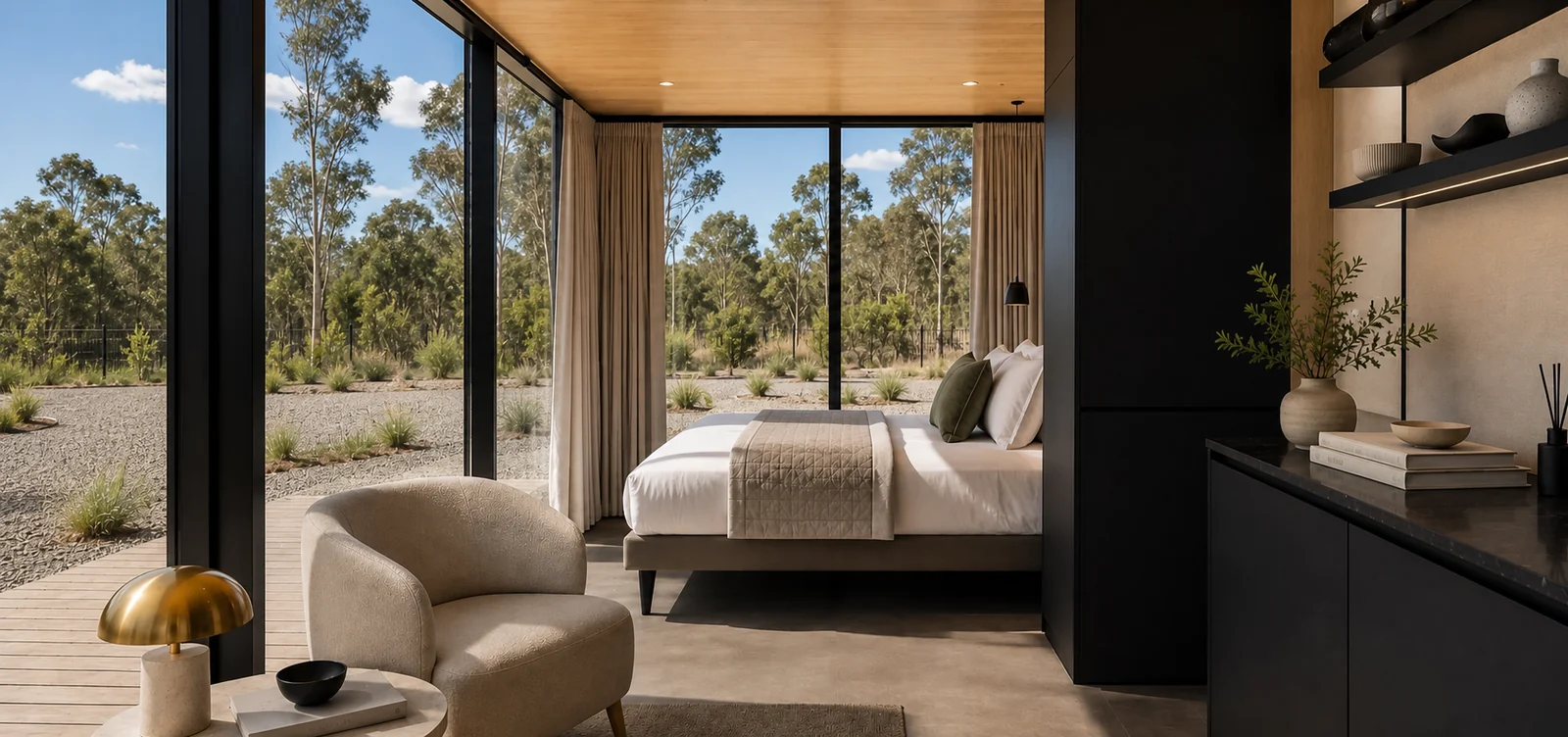 Inside the wide 5.8 m mirror house, bed against the far wall, a boucle armchair by the glazed corner and a black joinery run with open shelves