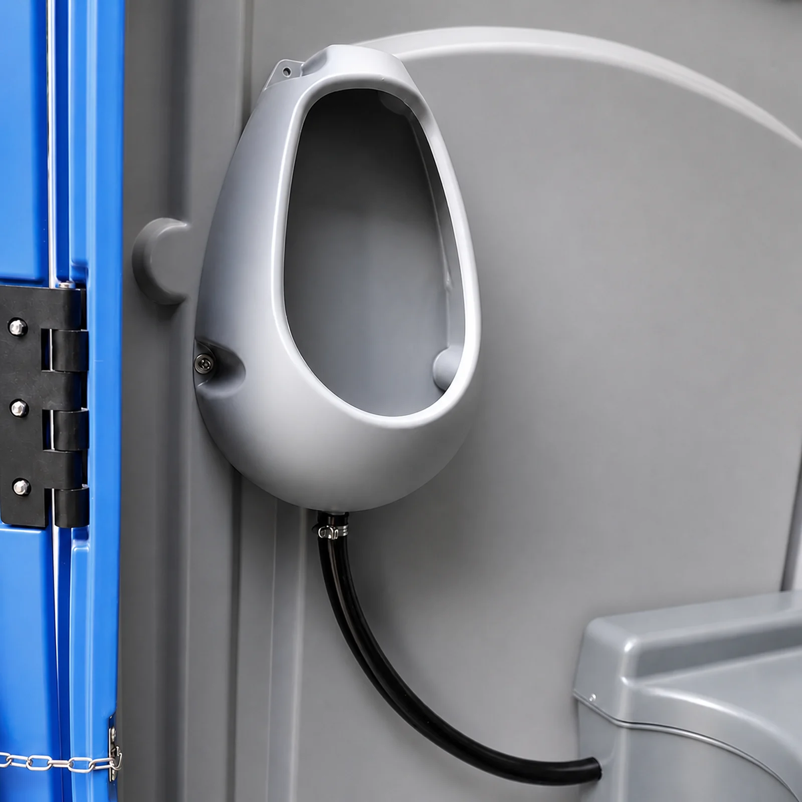 Close view of the wall mounted urinal inside the portaloo, moulded grey plastic with a black drain hose and the door hinge alongside