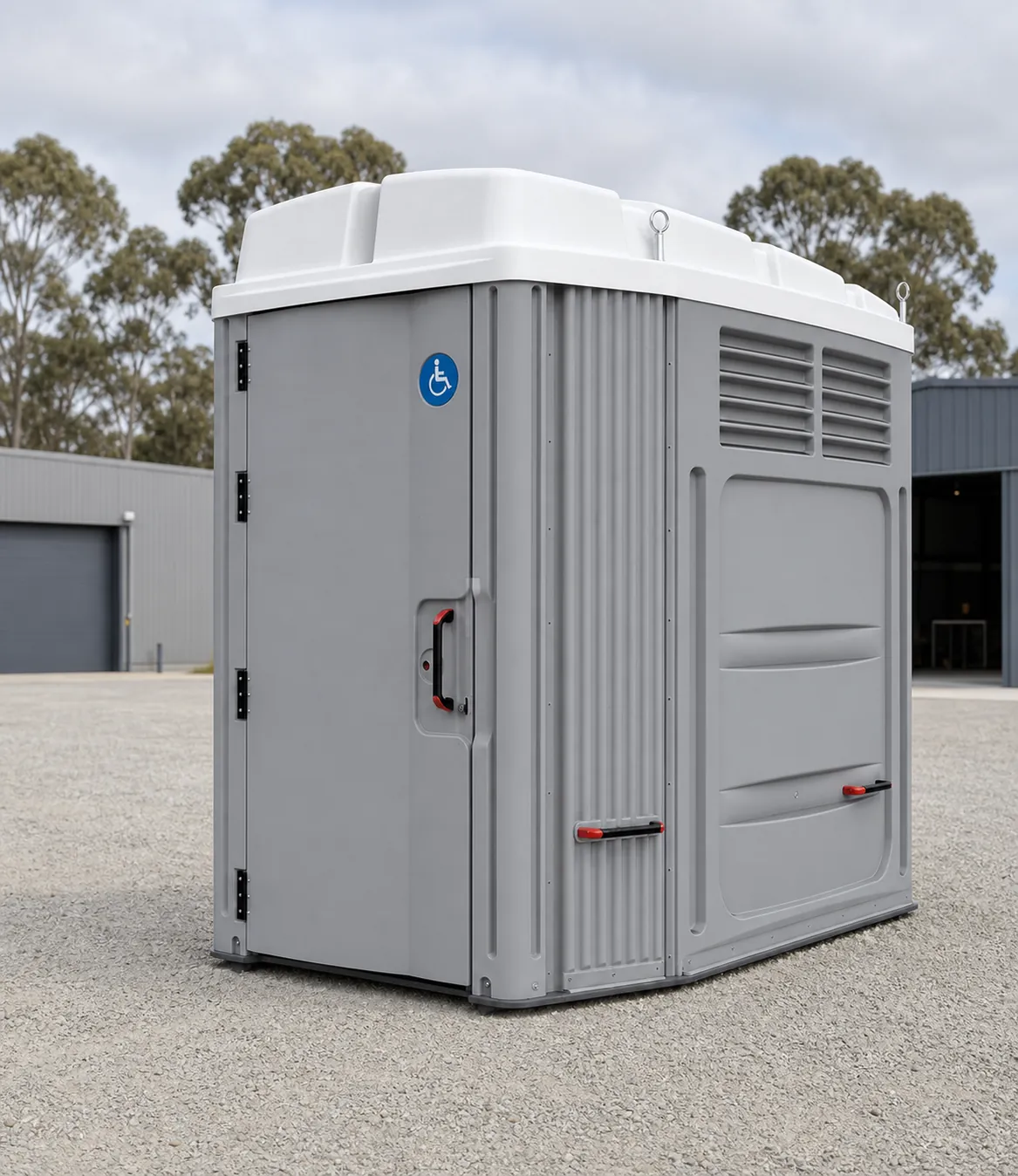 Wide grey moulded accessible portable toilet with a white roof, red locking handles and a blue wheelchair symbol on the door