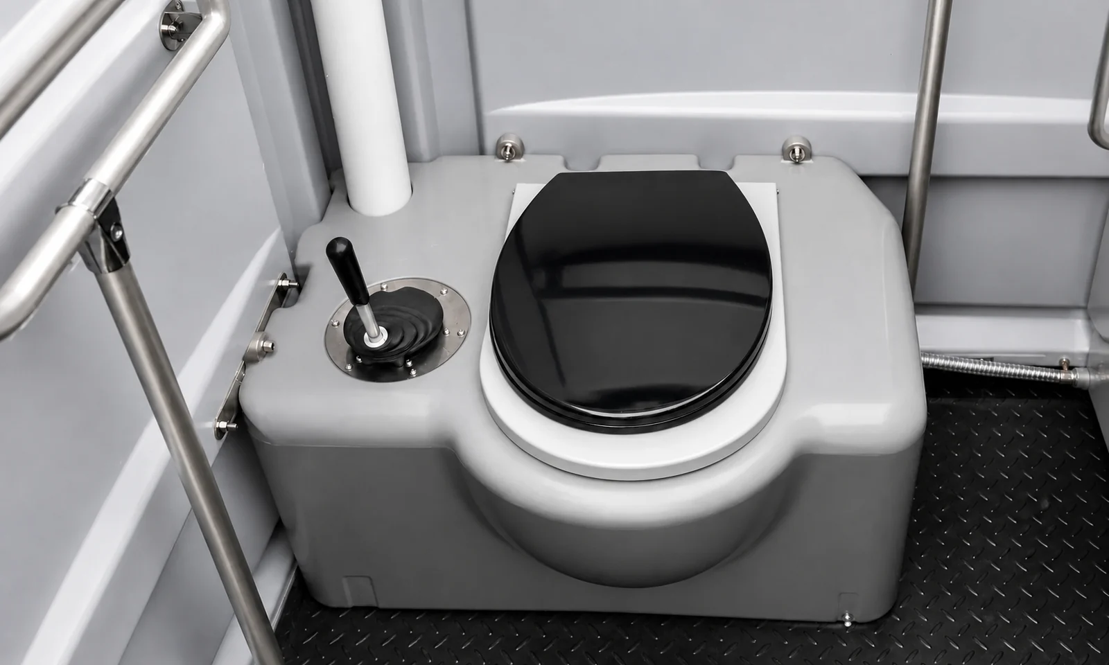 Close view of the moulded toilet with a black seat, foot flush pedal and stainless grab rails either side