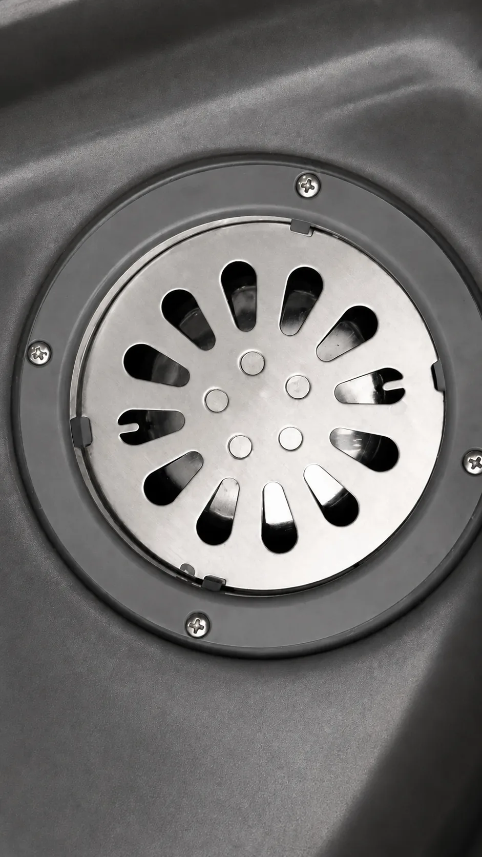 Close view of the stainless floor drain grate set into the moulded grey floor pan