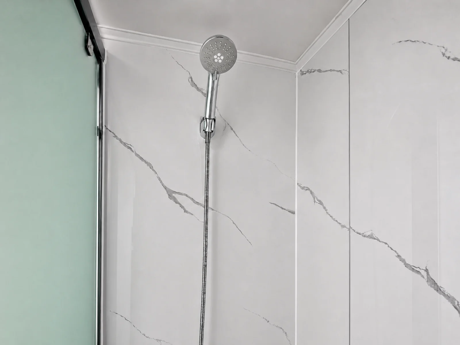 Shower recess in the portable bathroom, hand shower on a rail against marble look wall panels beside a green tinted sliding screen
