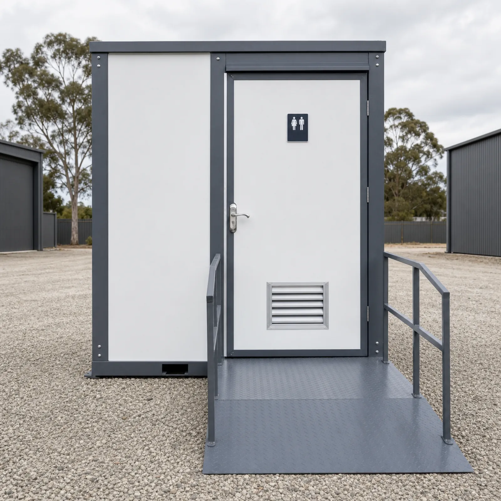 The accessible toilet cabin square on, unisex sign on the door, floor vent below and the chequer plate ramp with rails on both sides