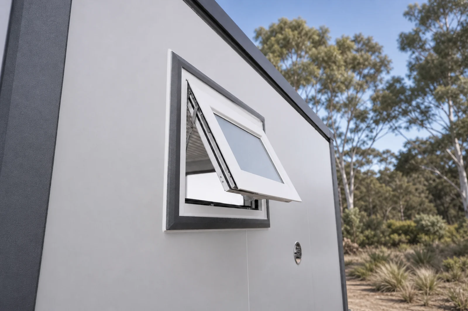 Awning window on the accessible cabin propped open on its stay, set in a grey frame in the white wall panel