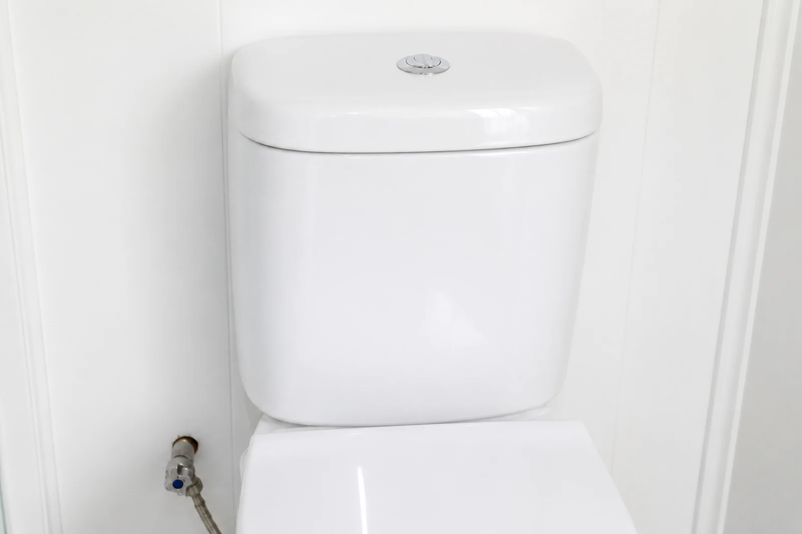 Close coupled toilet in the designer pod against a white wall with the water connection visible at floor level