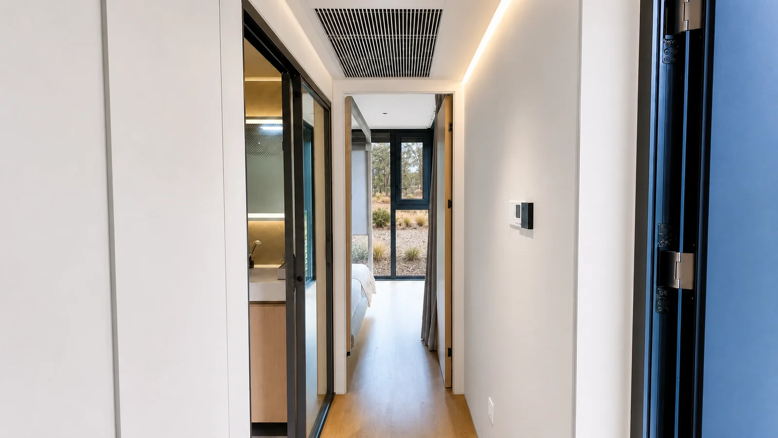 Corridor in the timber clad capsule looking past the bathroom door to the bedroom and the glazed end wall beyond