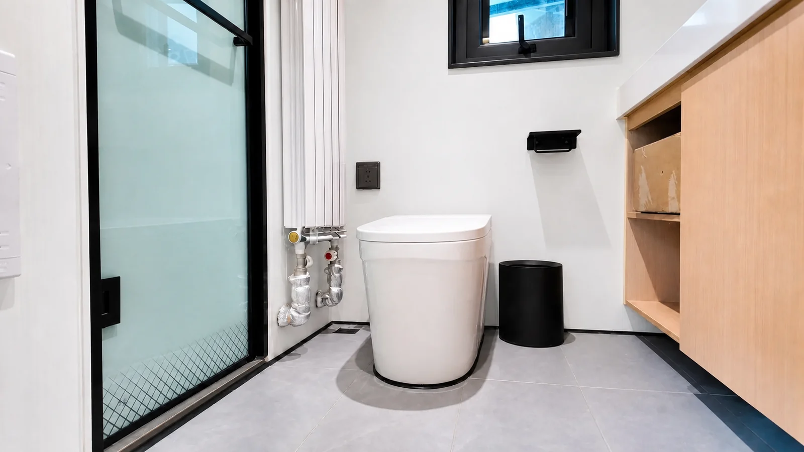 Toilet in the 9.5 m timber clad capsule next to a frosted glass shower door, with a timber vanity and a small window above